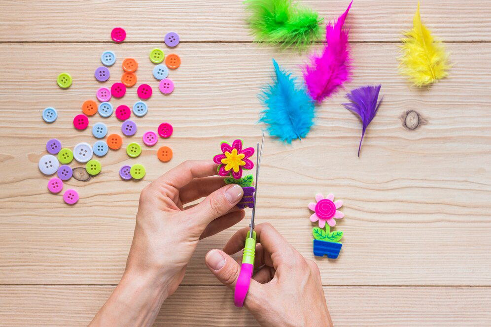 A person cutting colorful felt flower decorations with scissors.
